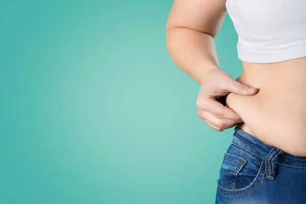 Image of woman pinching her love handles to show weight gain Healey